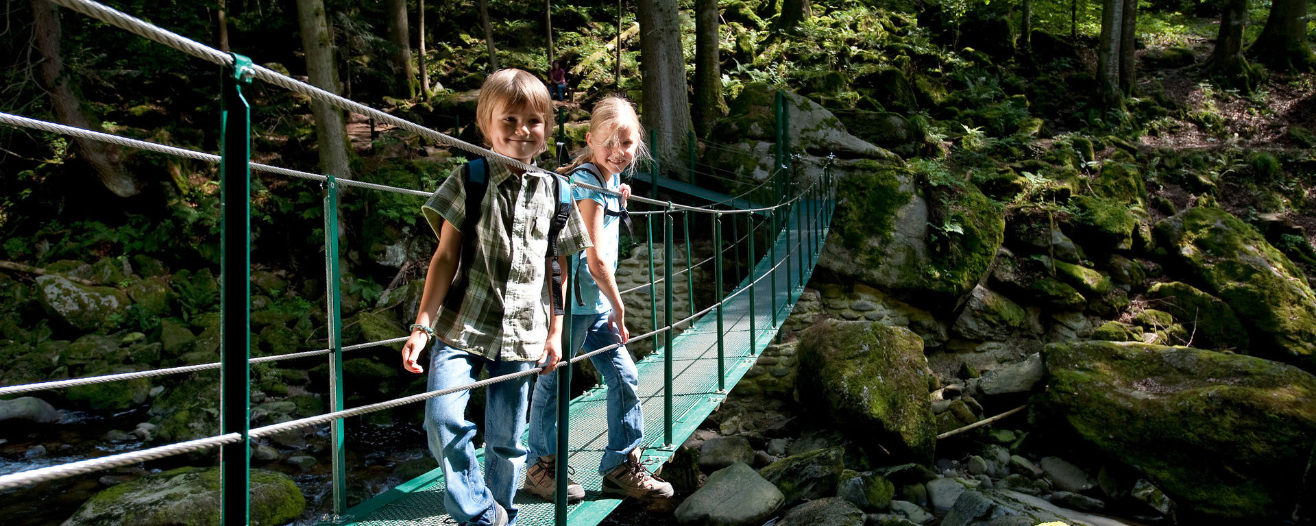 Kinder auf einer Brücke über vielen Steinen