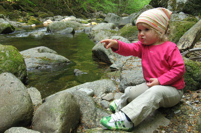 Kleines Mädchen beim Wandern zeigt auf große Steine, die sie entdeckt hat