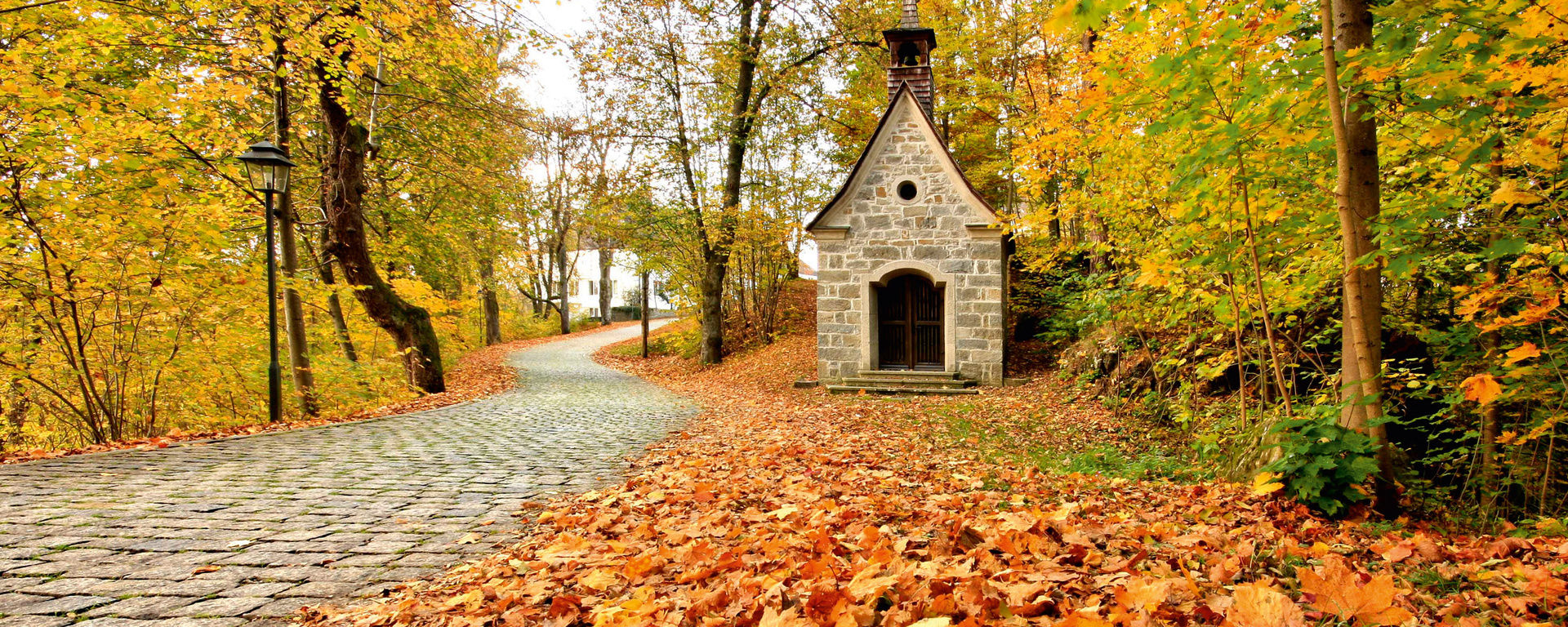 Kleine Kapelle am Wegesrand in mitten von buntem Laub