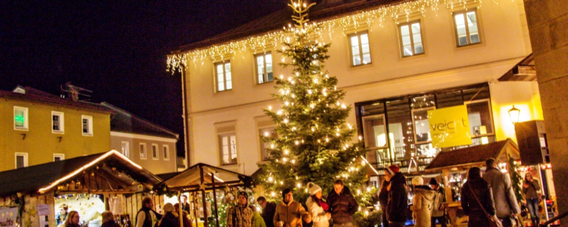 Weihnachtsmarkt bei Nacht mit kleinen Buden