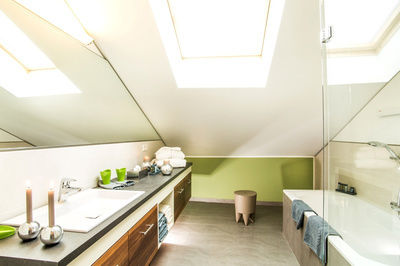 Modernes, liebevoll eingerichtetes Badezimmer mit Dachschräge und großem Spiegel