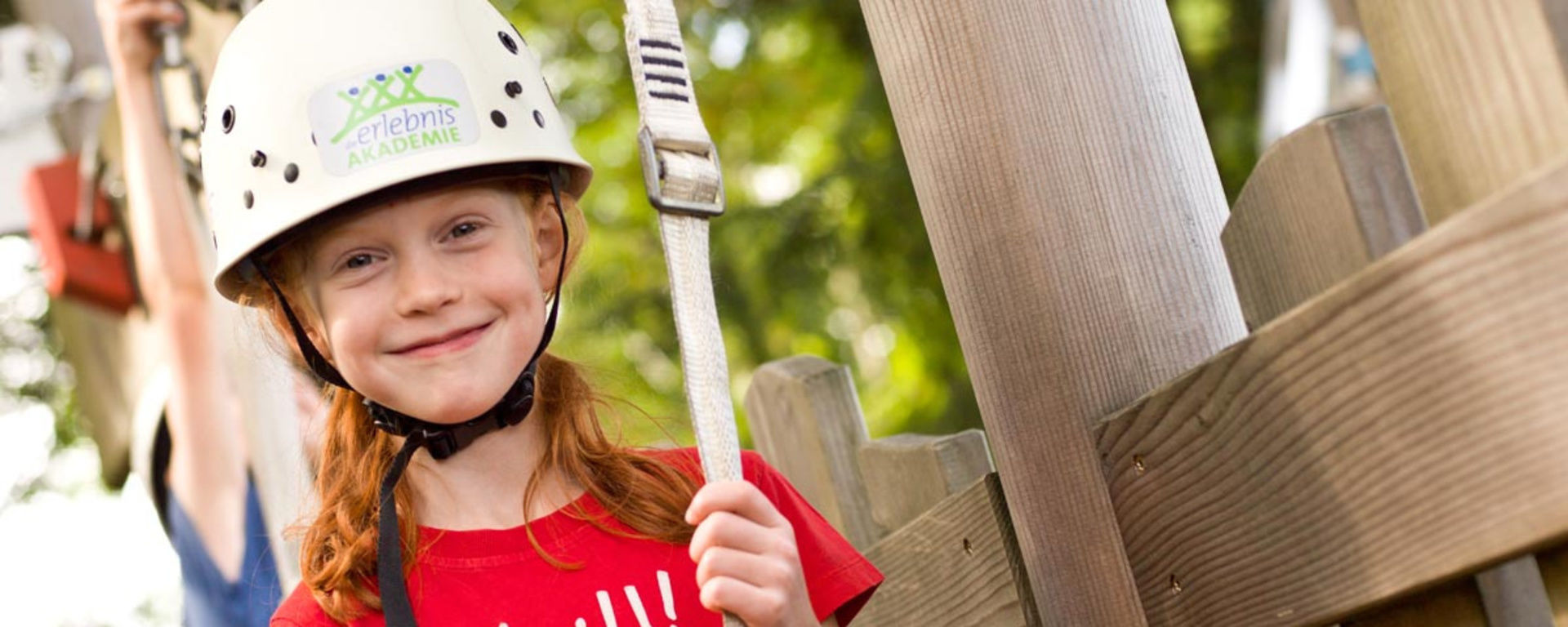 Mädchen grinst beim Klettern im Kletterpark
