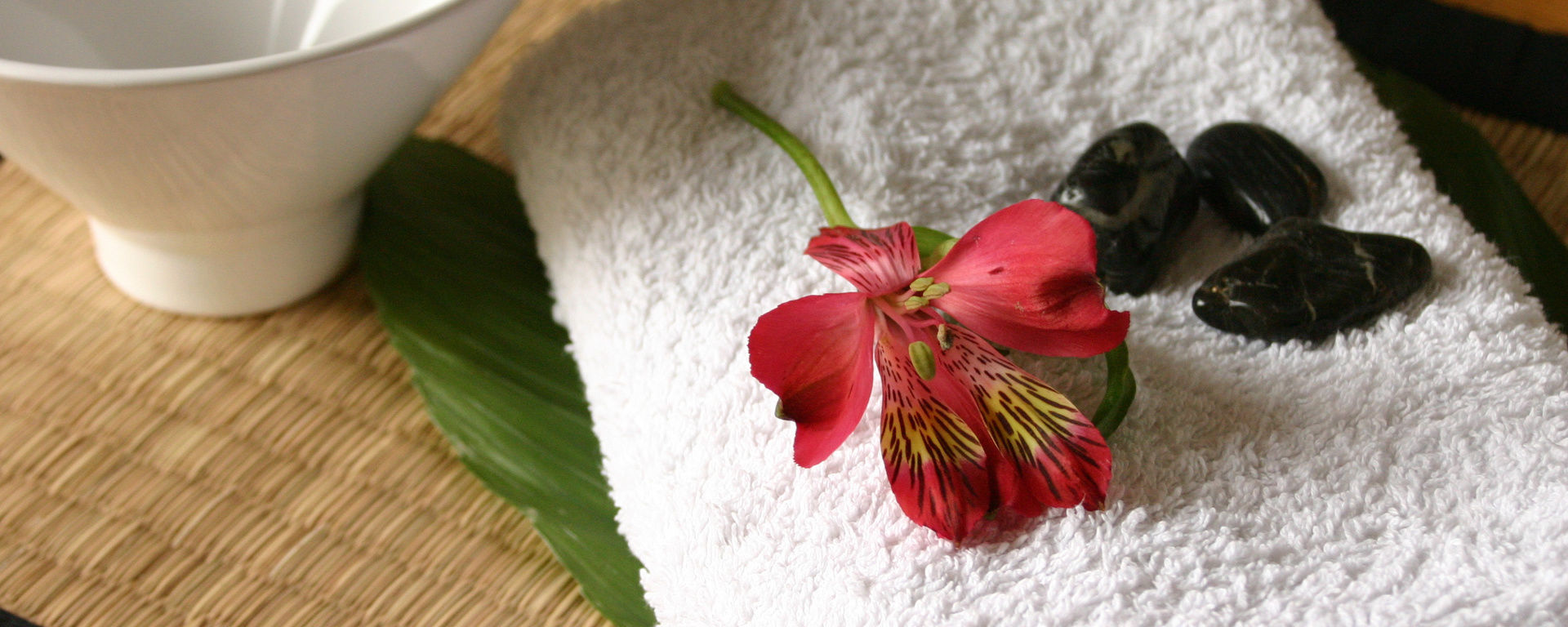 Saunatuch mit Steinen und Blumen für eine Massage