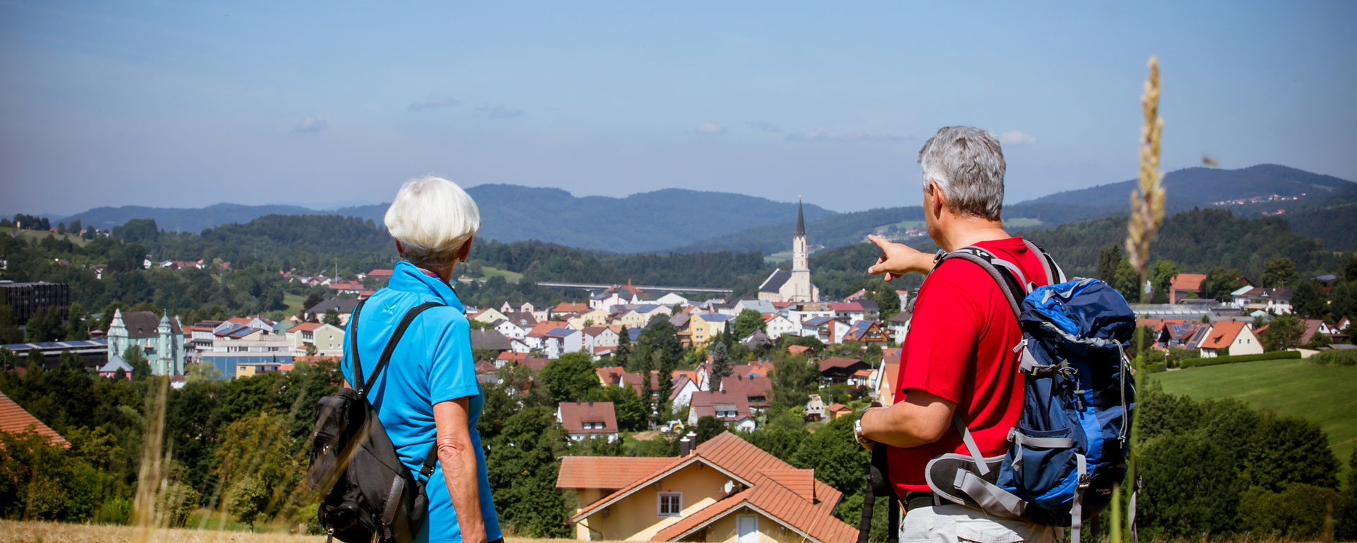 Zwei Wanderer blicken über Freyung und zeigen auf die Kirche