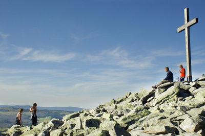 Gipfelkreuz mit ein paar Menschen, die den Ausblick genießen