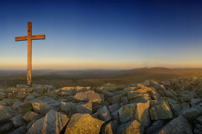 Gipfelkreuz am Lusen auf großen Steinen vor einer malerischen Aussicht in die Weite des Bayerischen Waldes